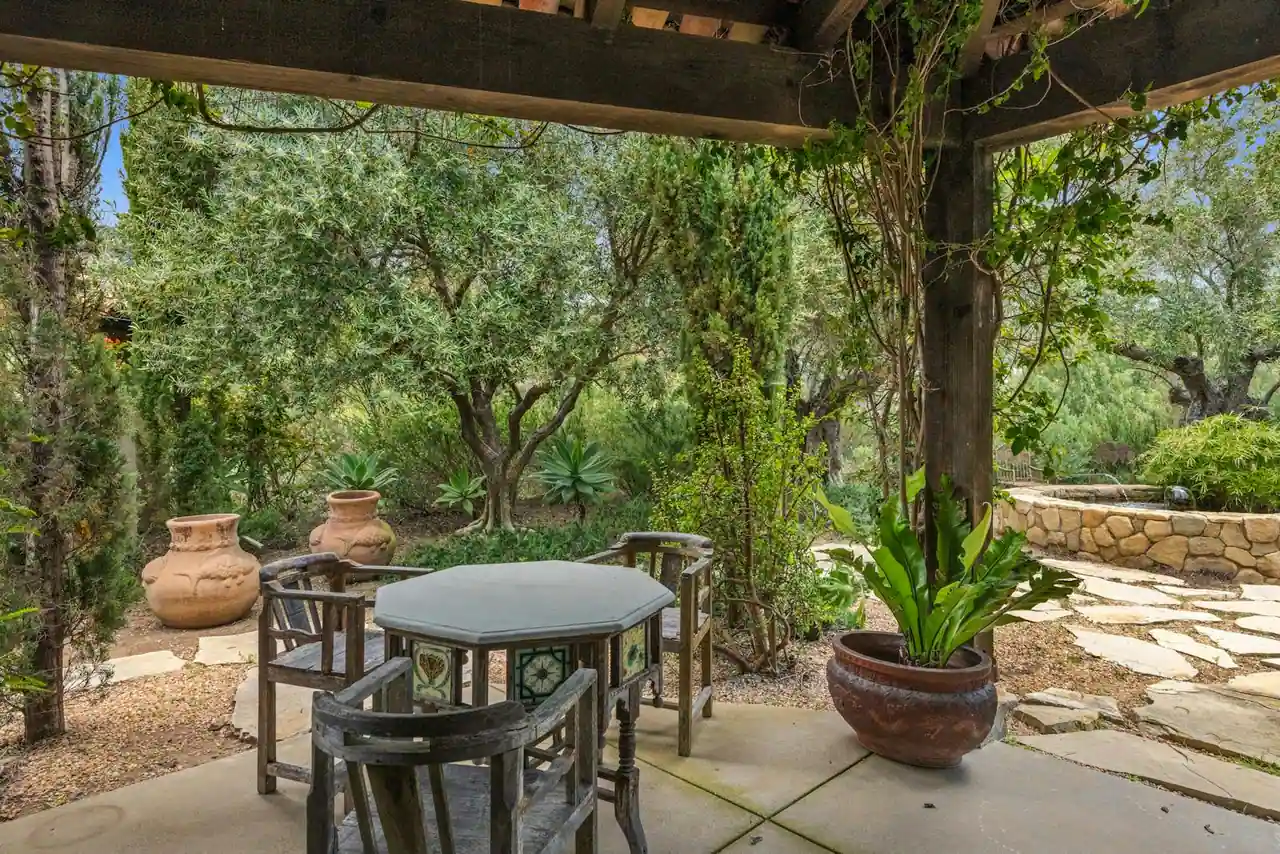 Jardin contemporain aménagé avec mobilier en bois huilé, grandes jardinières en terre cuite et éclairage chaud du soir