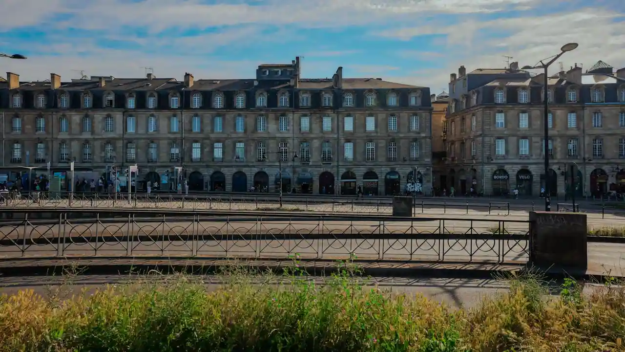 Façade haussmannienne du centre de Bordeaux avec pierre claire et balcons en fer forgé, sous un ciel lumineux
