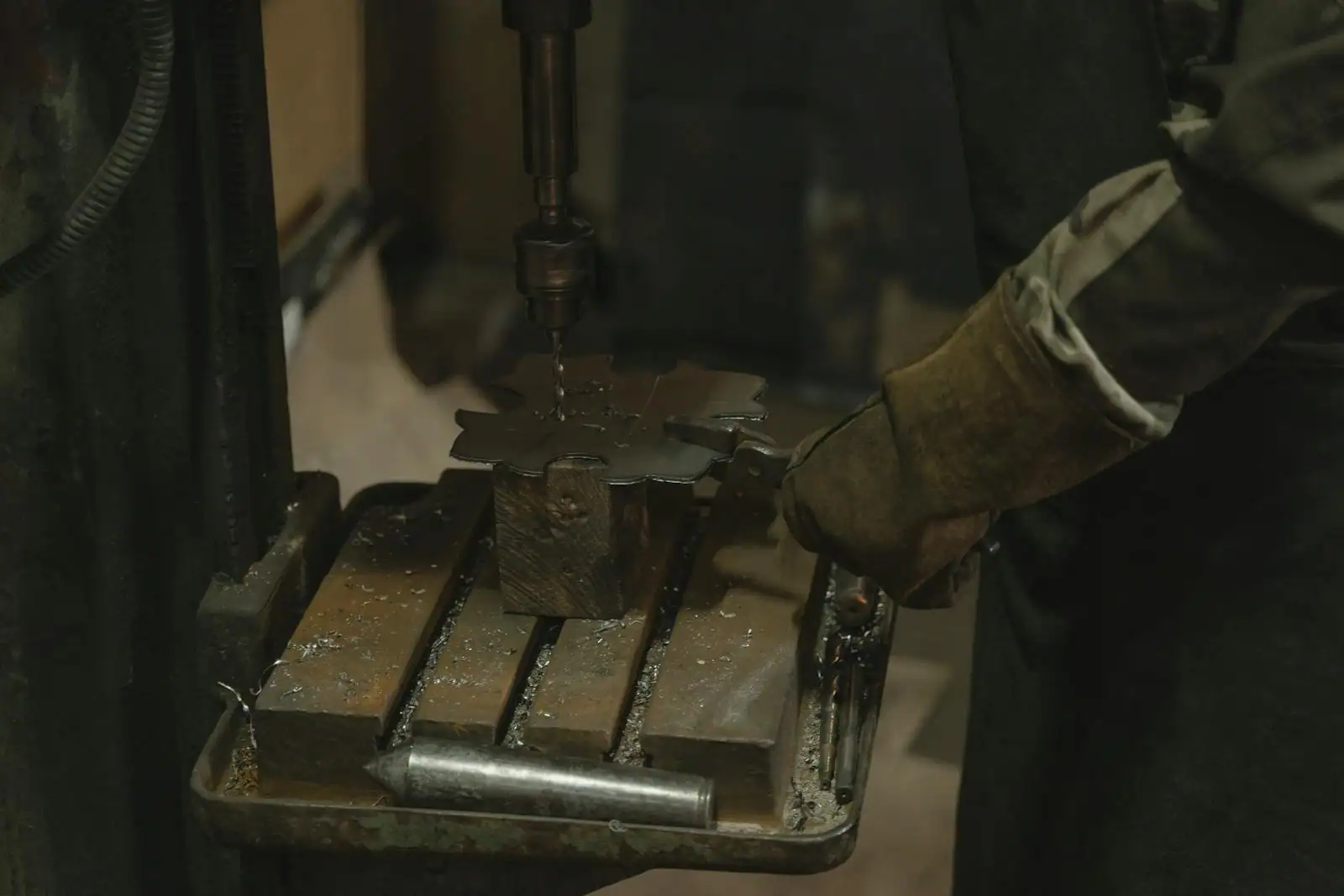 Perceuse à colonne d'atelier en fonctionnement, broche descendant sur une pièce métallique bridée