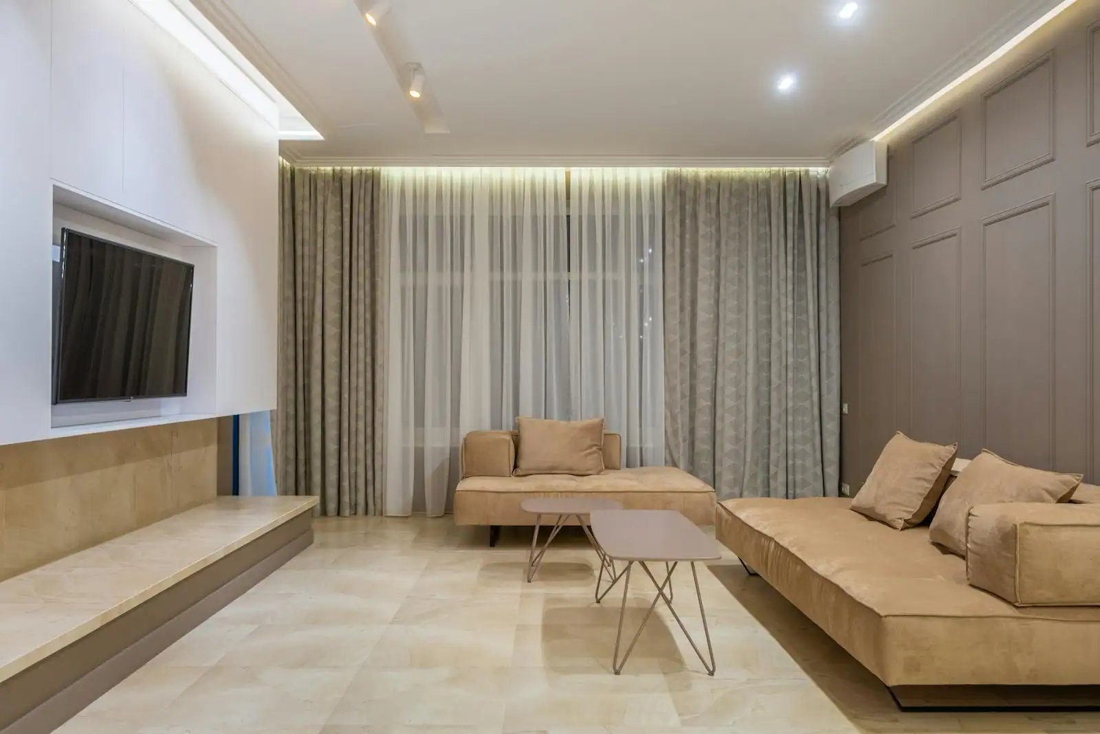 Salon contemporain lumineux avec canapé en lin écru, table basse en bois clair, parquet à chevrons et grande baie vitrée