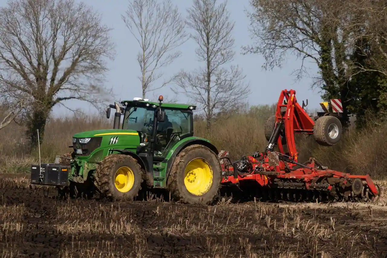 Tracteur agricole tirant un outil dans un champ labouré à la campagne