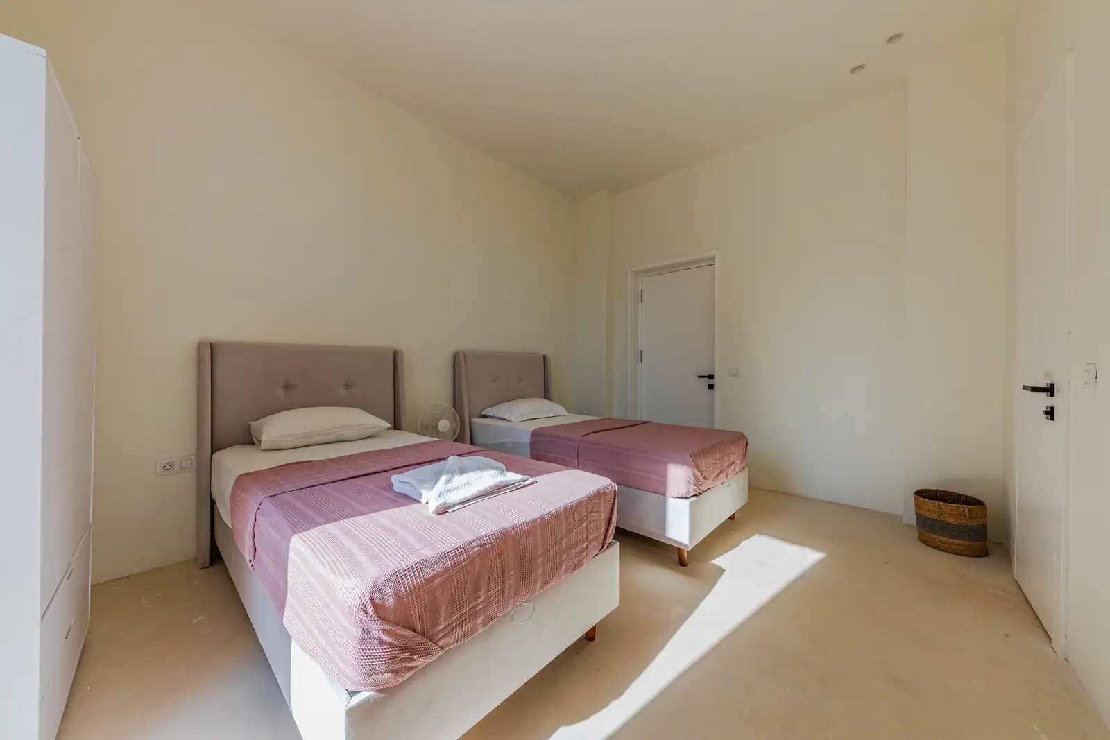 Chambre claire meublée de deux lits simples à têtes de lit capitonnées, baignée de lumière naturelle