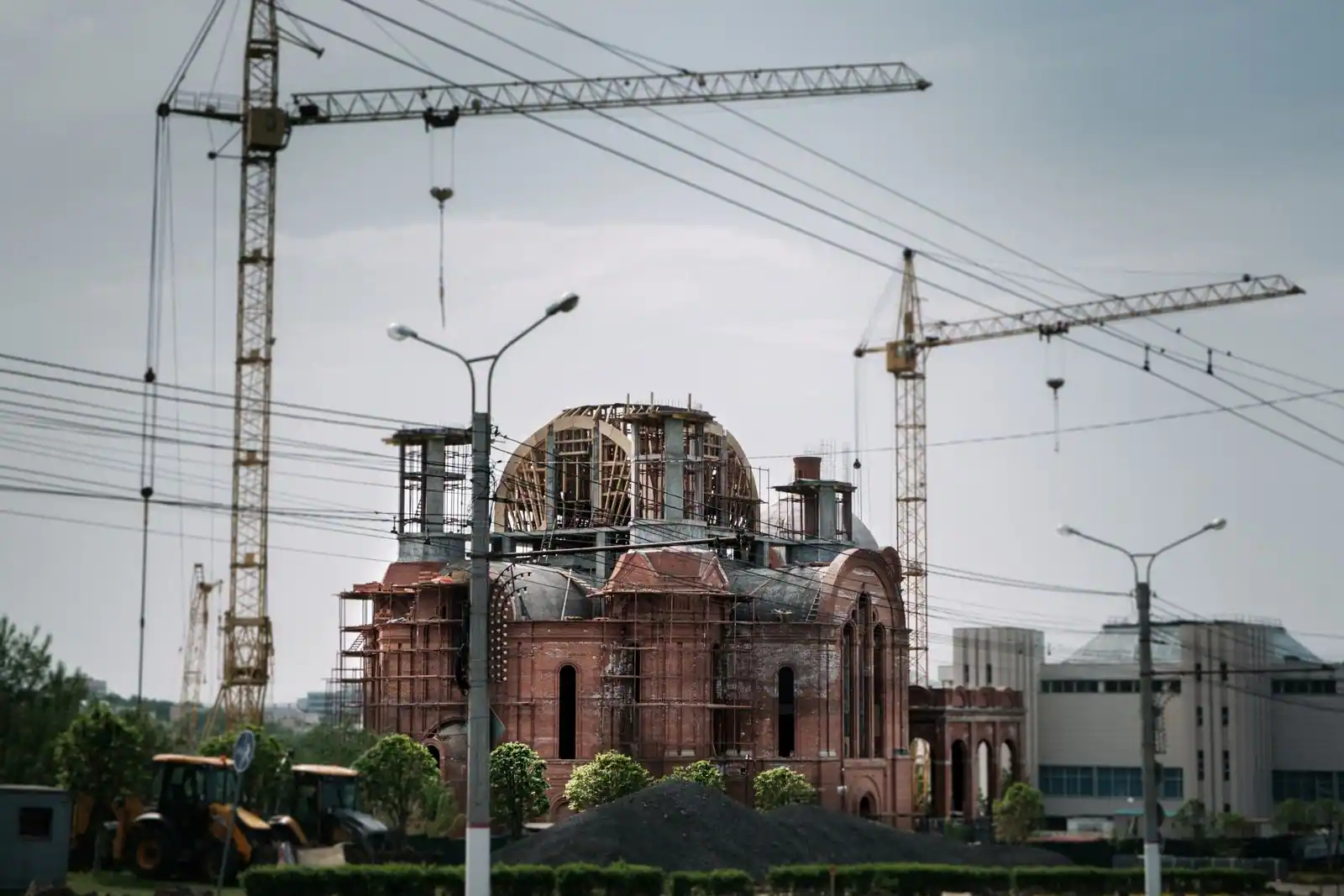 Chantier de construction d'un grand bâtiment en brique entouré de grues et d'échafaudages