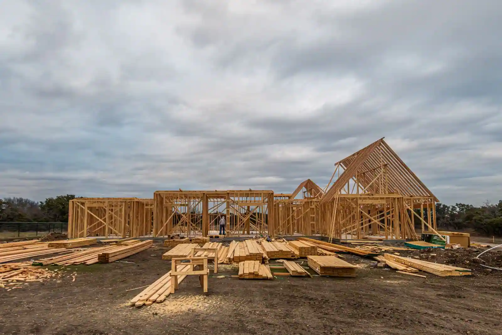 Maison individuelle en cours de construction, murs montés et charpente apparente sur un chantier résidentiel