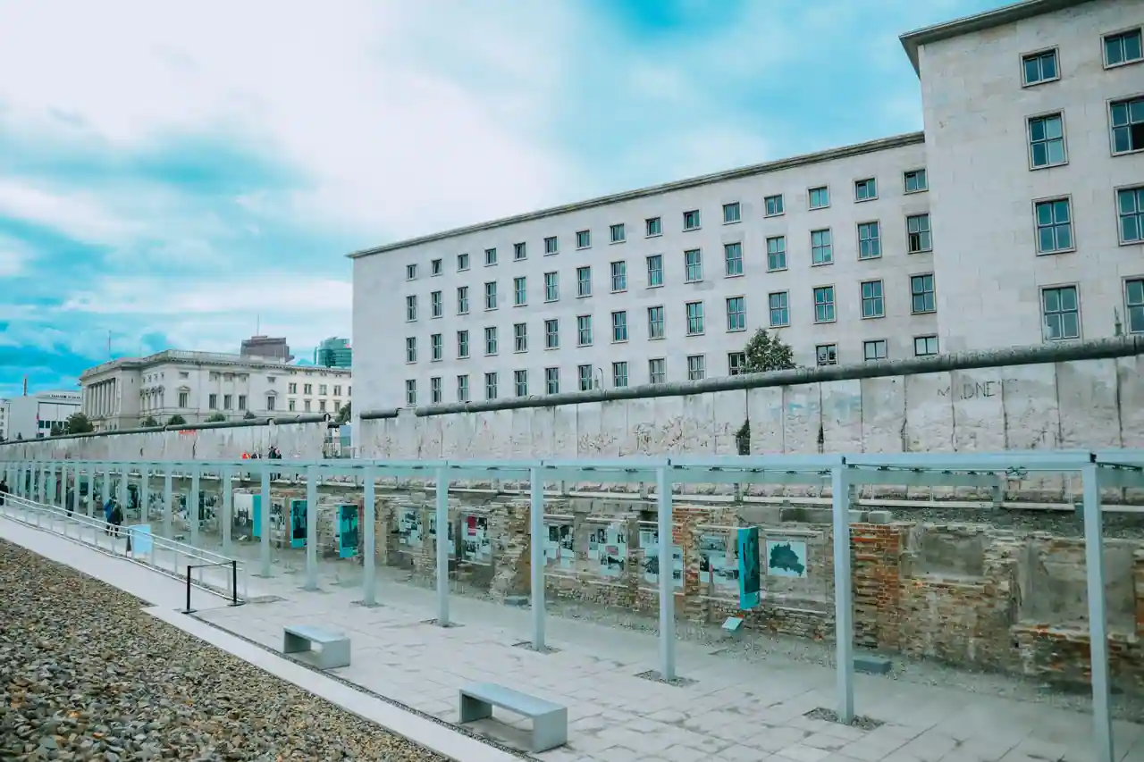 Section conservée du mur de Berlin longeant une esplanade, devant un grand bâtiment ancien