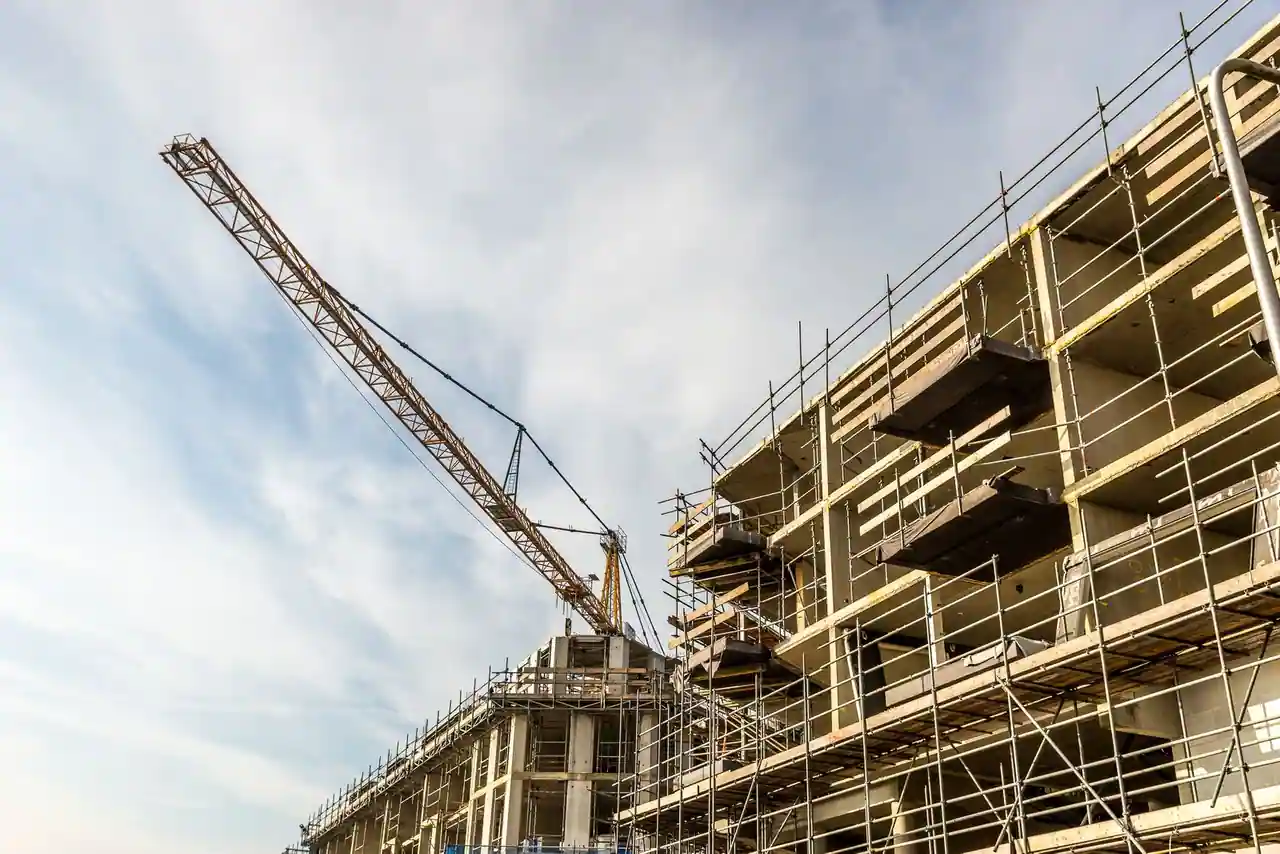 Bâtiment en cours de construction entouré d'échafaudages, avec une grue dressée sur le chantier