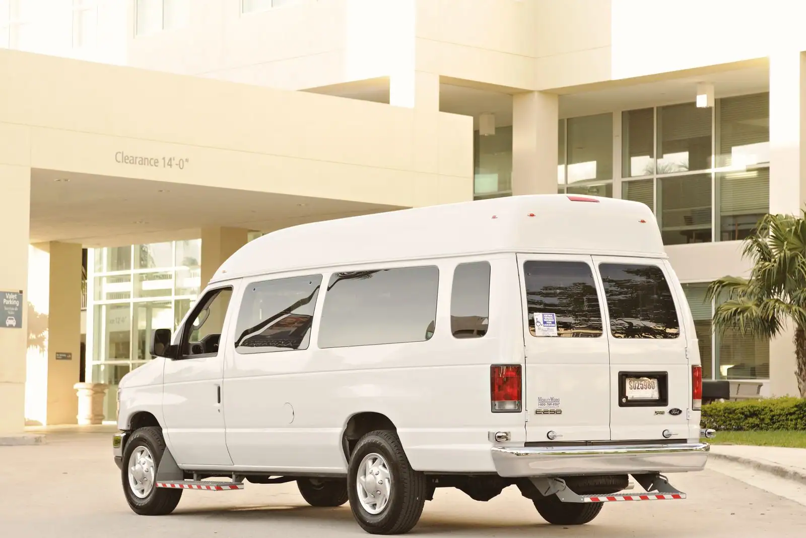 Minibus de couleur claire pour le transport de passagers, stationné à l extérieur, vu de trois quarts arrière.