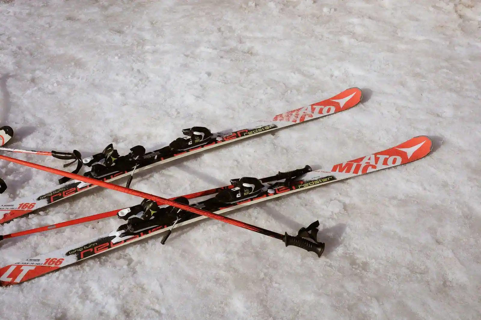Paire de skis alpins avec fixations et bâtons de ski posés sur la neige