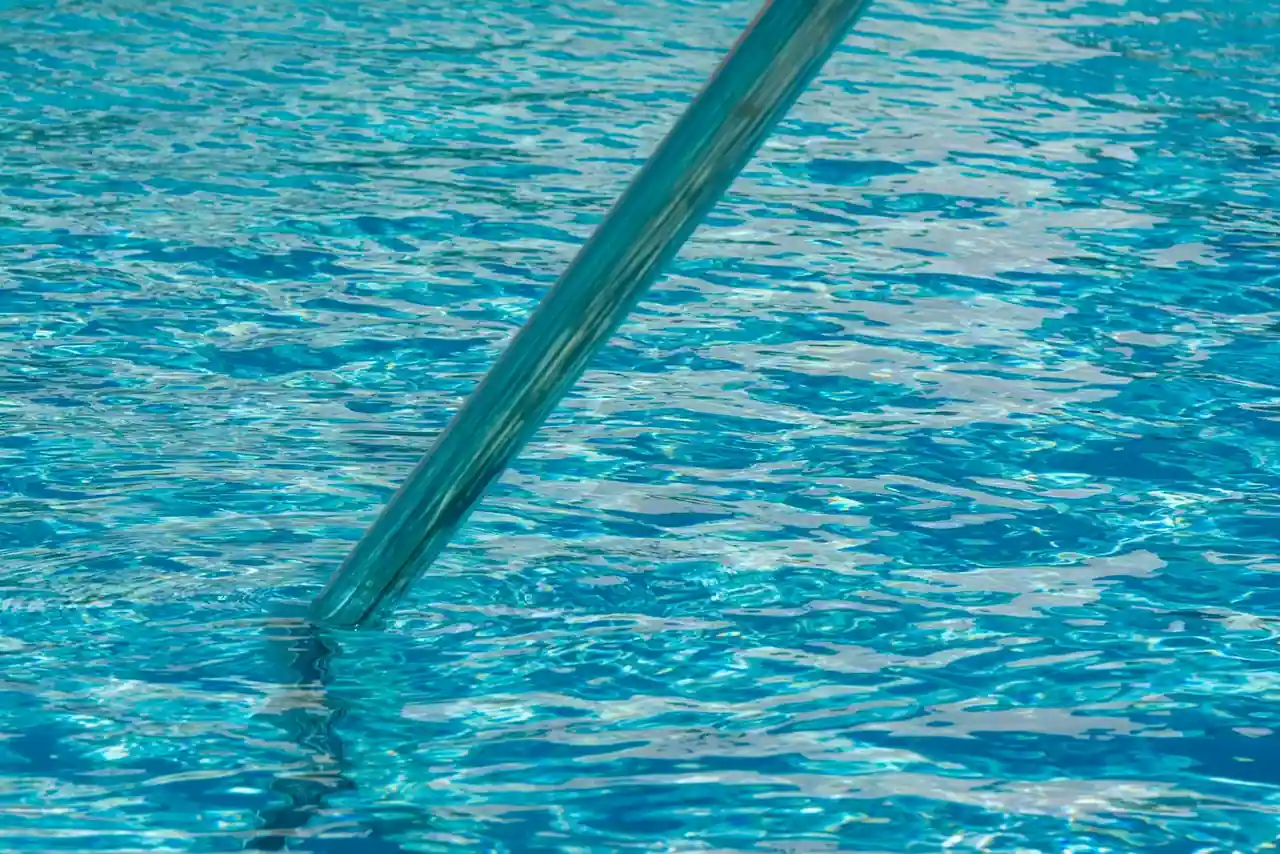 Galets de chlore et produits d'entretien posés au bord d'une piscine extérieure à l'eau claire