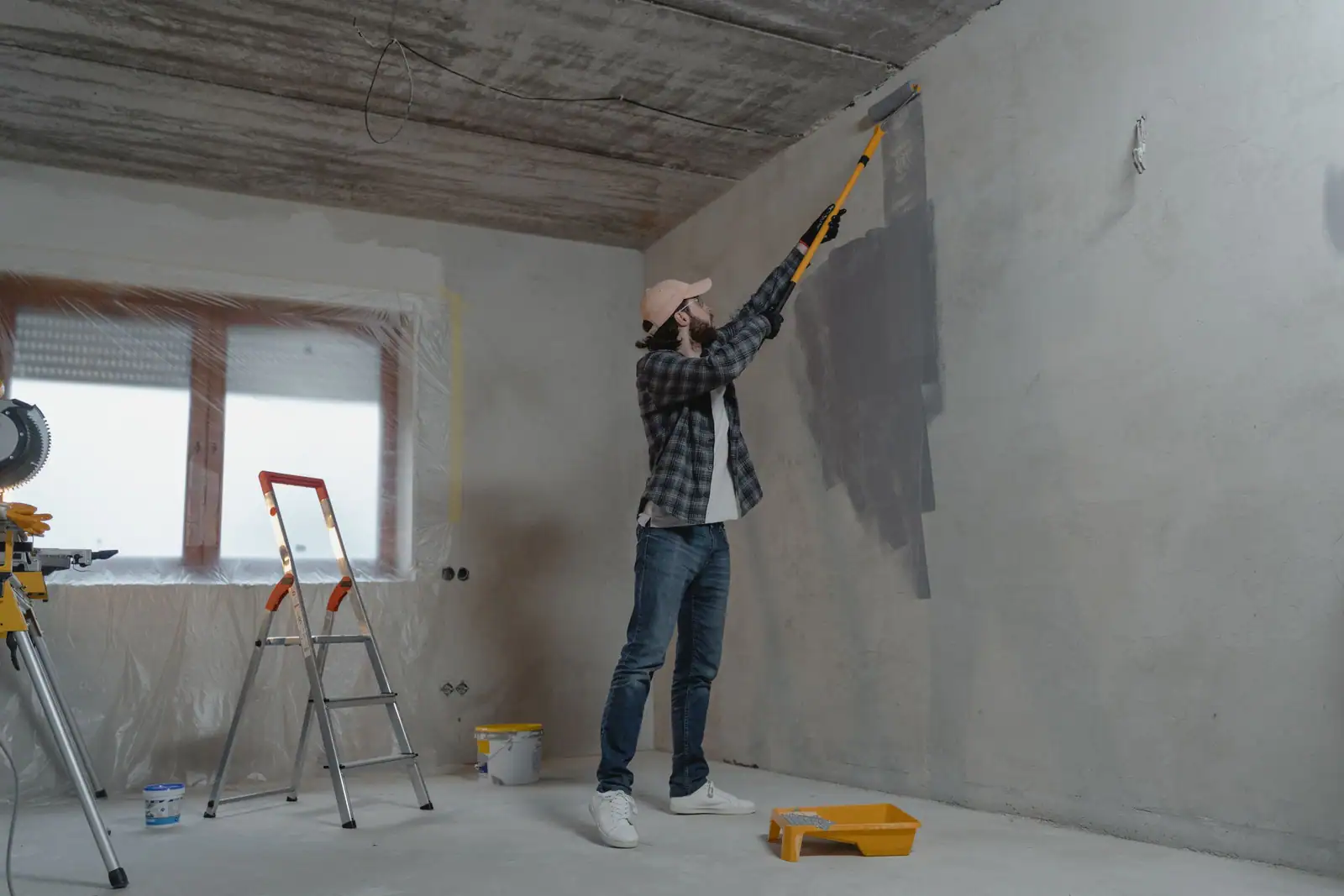 Peinture d’un mur au rouleau pendant des travaux d’intérieur, bricolage de saison à la maison.