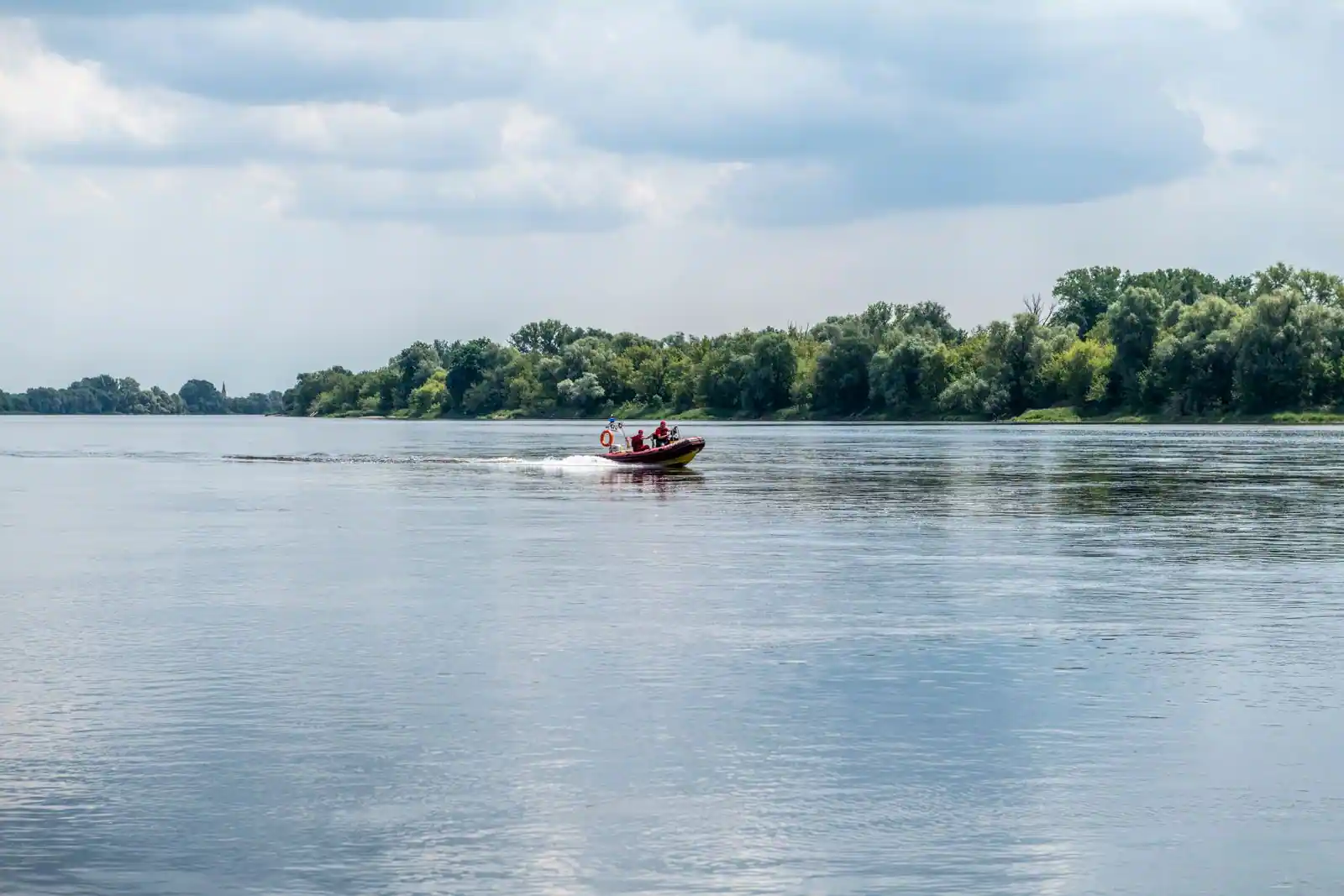 Petit bateau à moteur de plaisance sur une rivière calme, évoquant une location sans permis