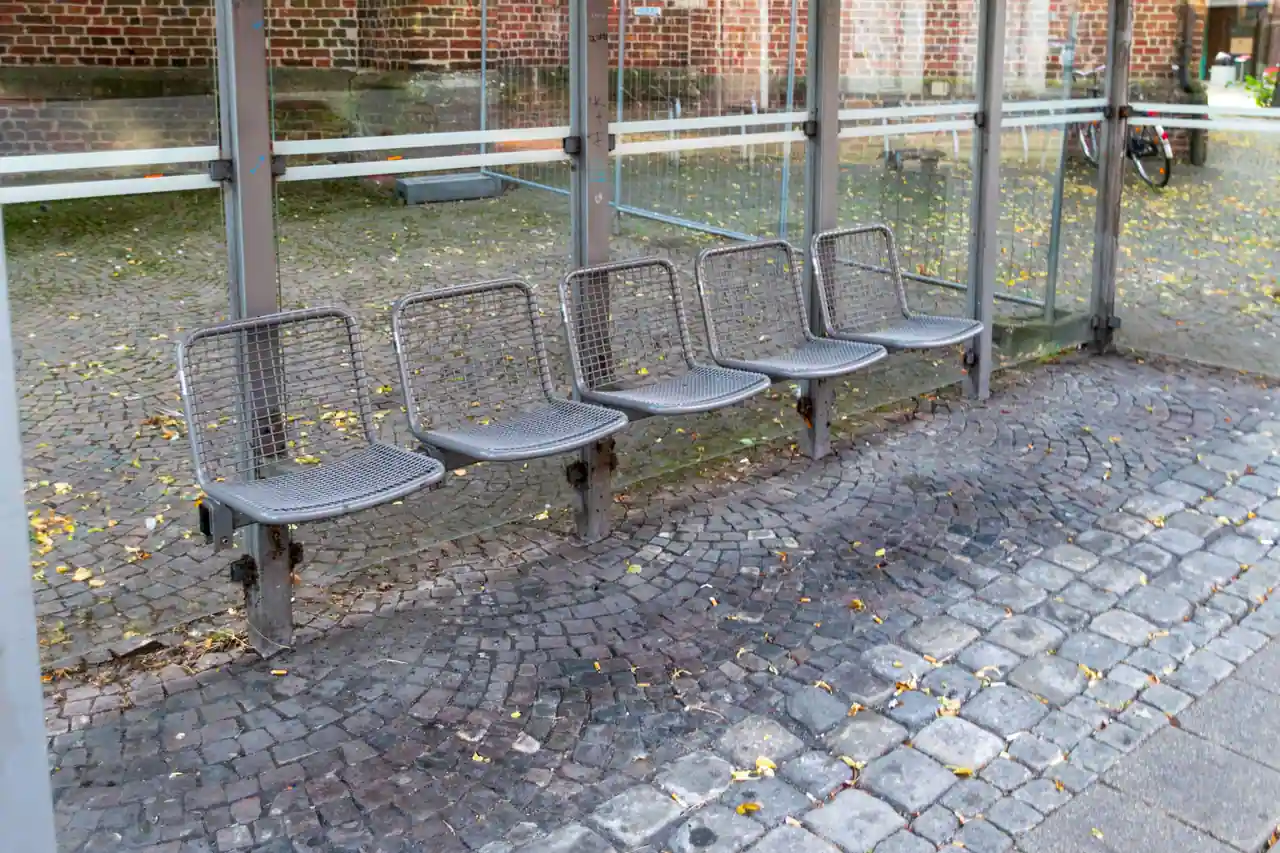Rangée d'assises individuelles en métal dans un abribus, un aménagement qui empêche de s'allonger