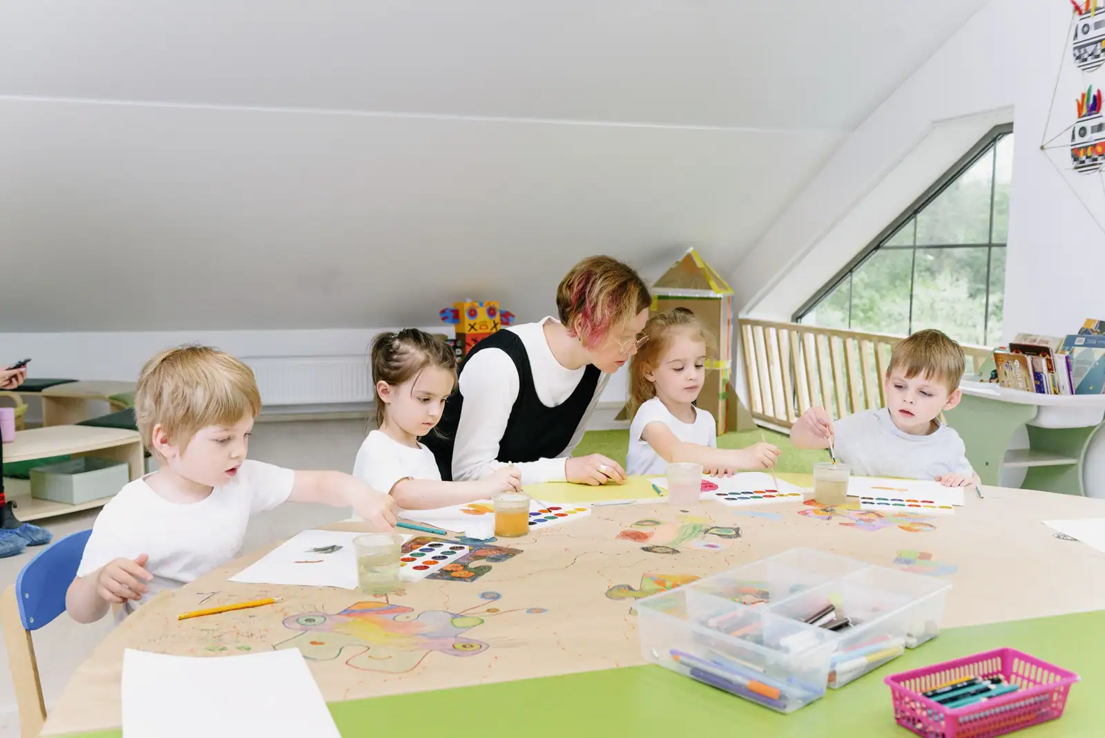 Atelier d'arts plastiques en maternelle : quatre enfants peignent autour d'une table avec une adulte