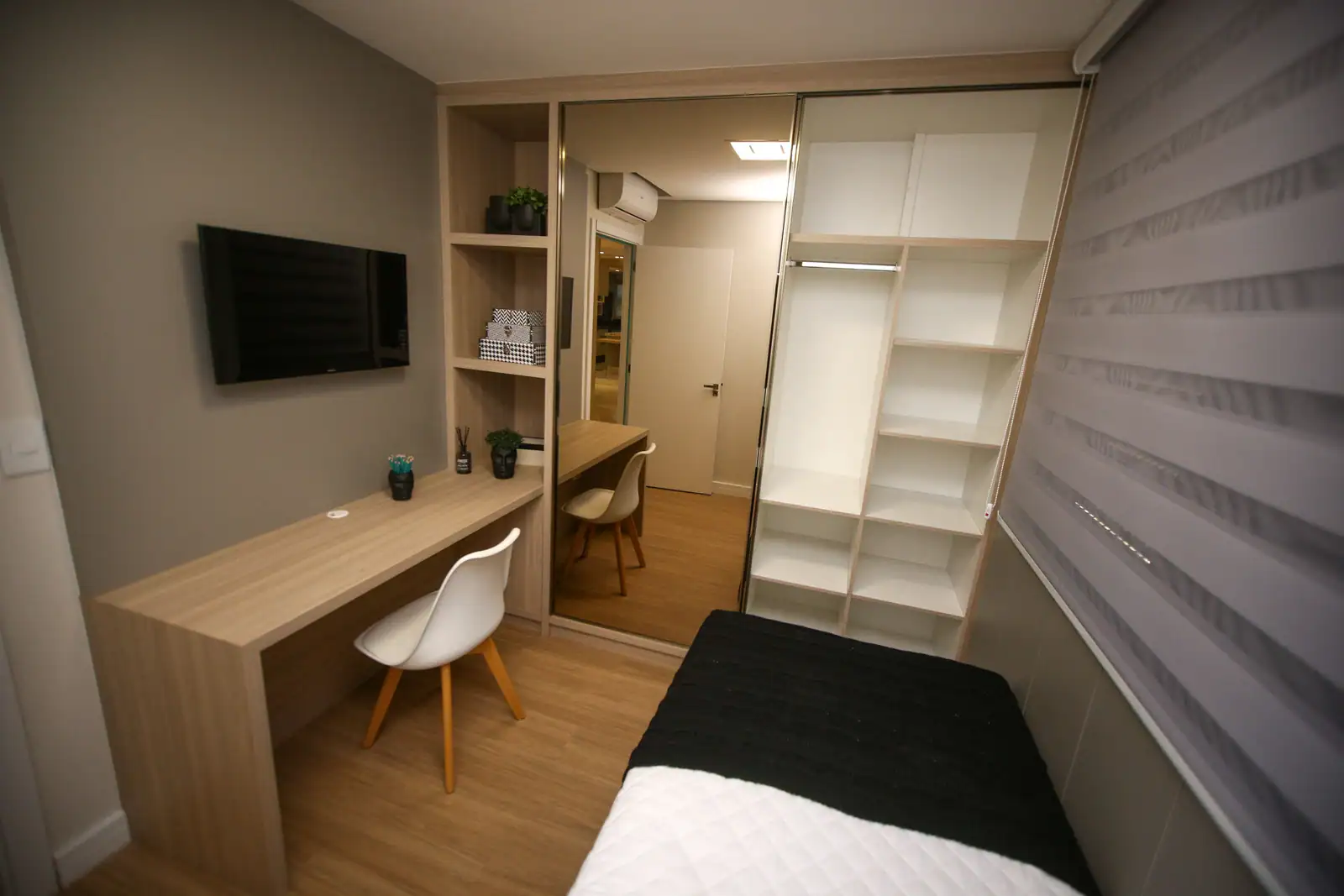 Petite chambre meublée équipée d'un bureau, d'une chaise et de rangements fermés, prête à louer