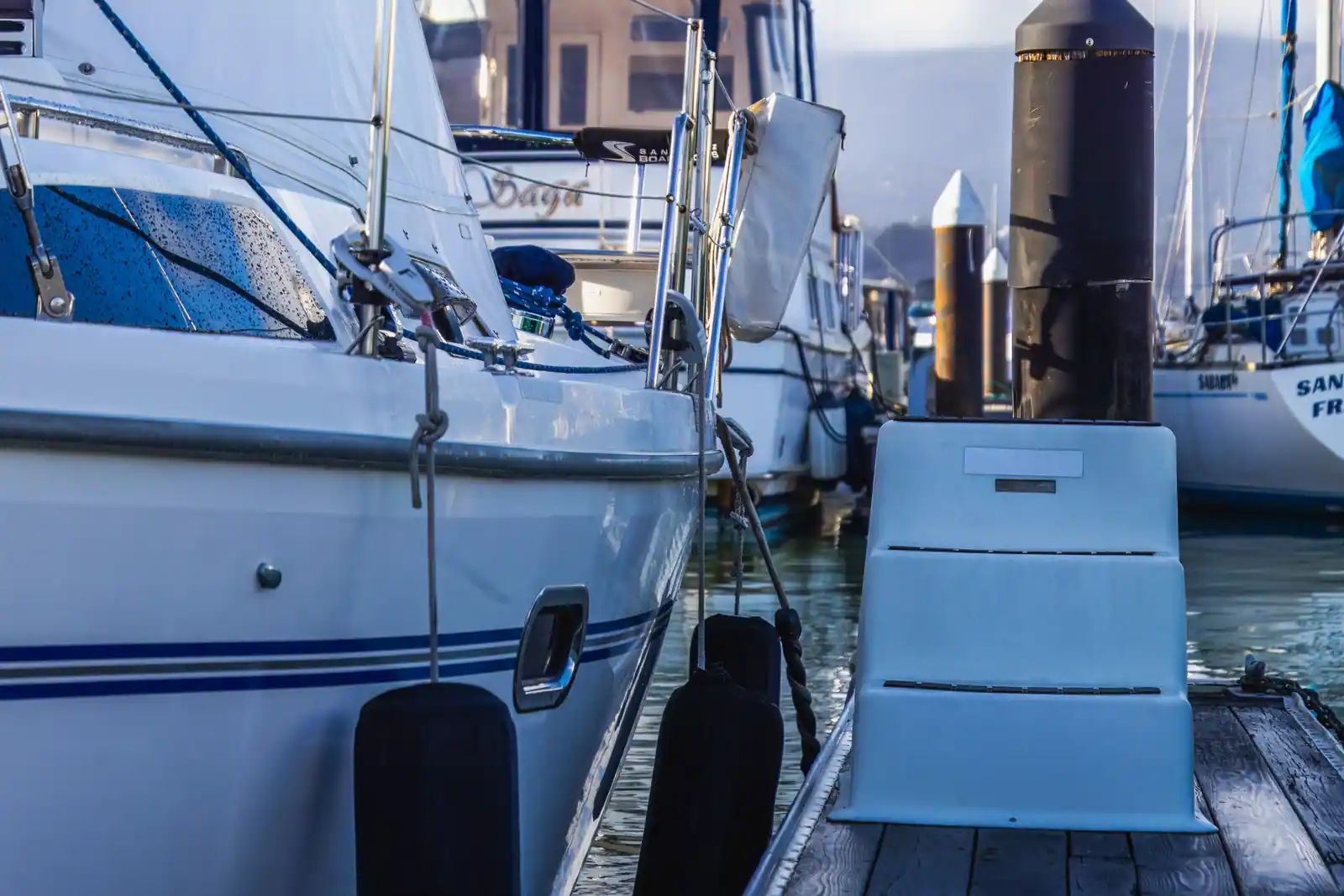 Bateau de plaisance à quai le long d'un ponton, pare-battages et amarres en place, marche d'embarquement